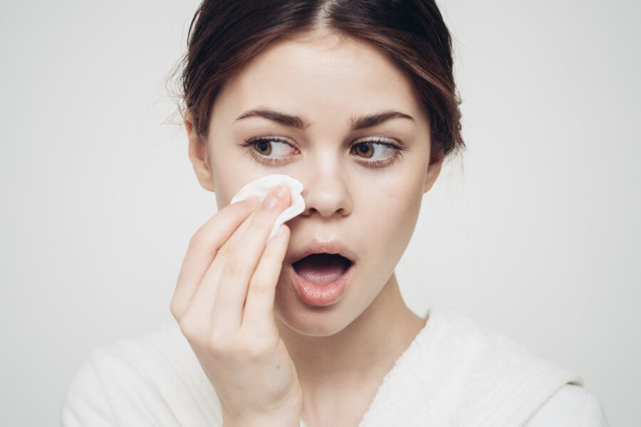 woman in a bathrobe wipes her face with a white sponge appearance care cosmetology