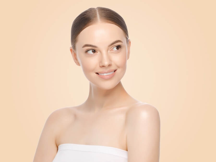 attractive young woman with tied hair looks rightwards isolated on brown background