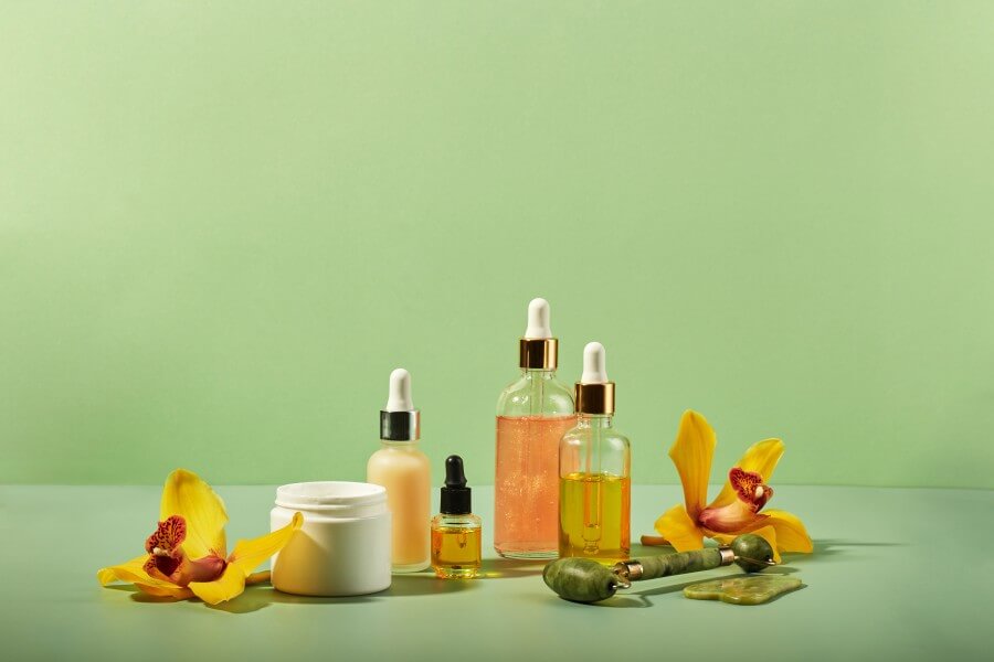 cosmetic care products in glass bottles with orchid flowers serums, cream, gel, oils. concept for face and body care, wellness and spa, tropical relaxation.