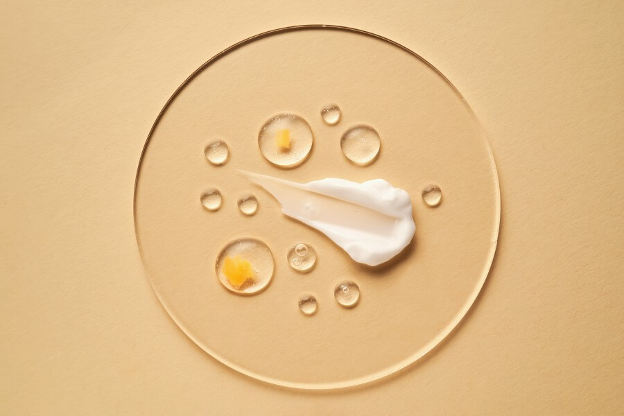 gel, serum and a cream on a transparent round stand on a beige background.