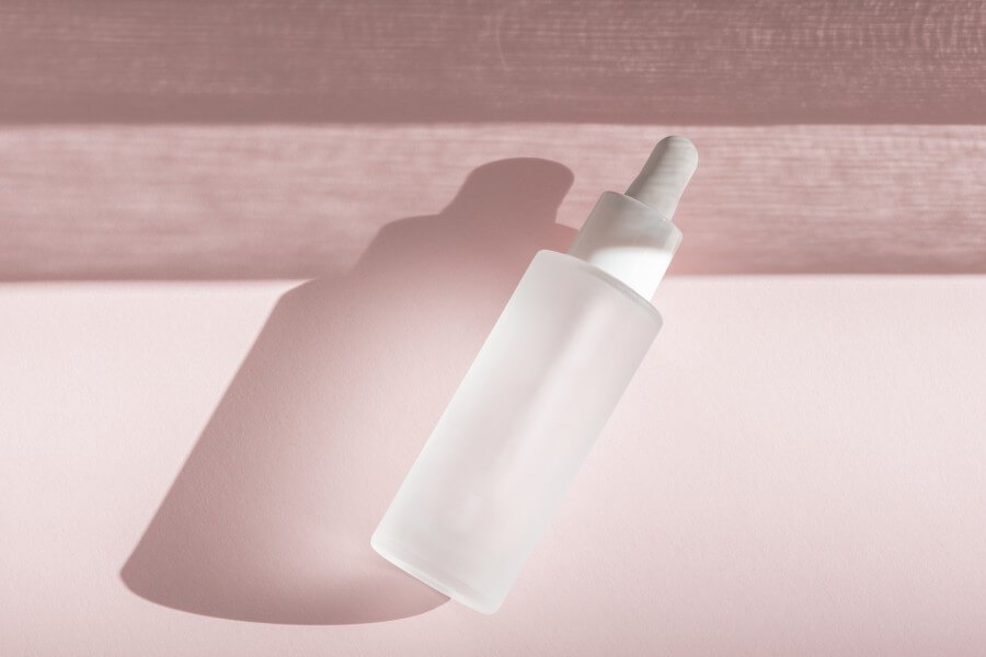 skin moisturizing serum on pink backdrop with shadow. beauty skincare essence mockup tincture flat lay, wellness packaging. hyaluronic acid oil mock up. lliquid product in glass bottle