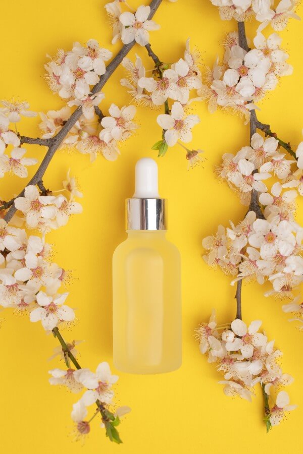 unbranded serum bottle and flowers on yellow backg 2023 11 27 05 34 24 utc