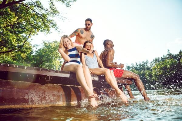 group of happy friends having fun while sitting and laughting on the pier on river