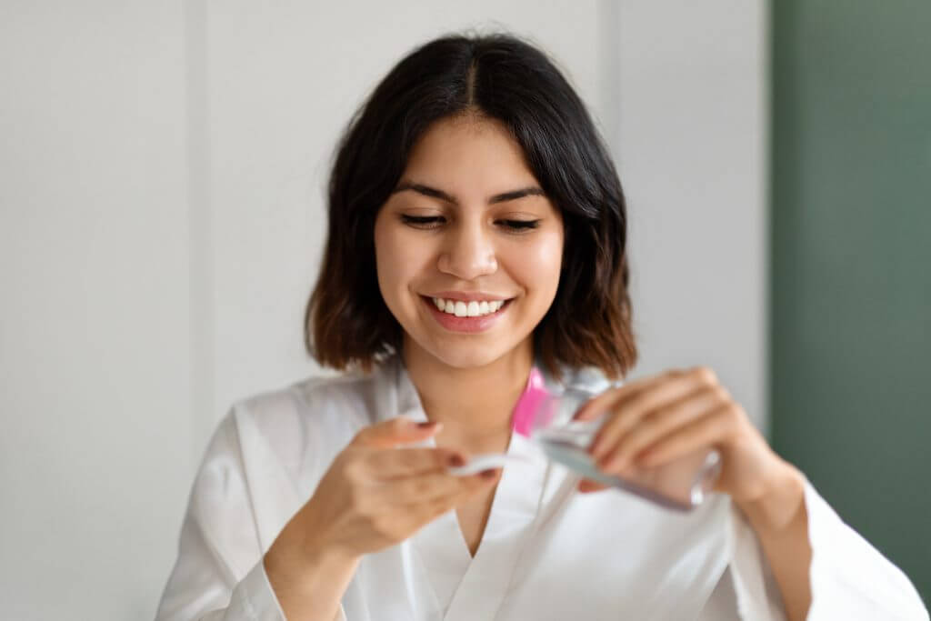 headshot of woman using micellar water and cotton pad