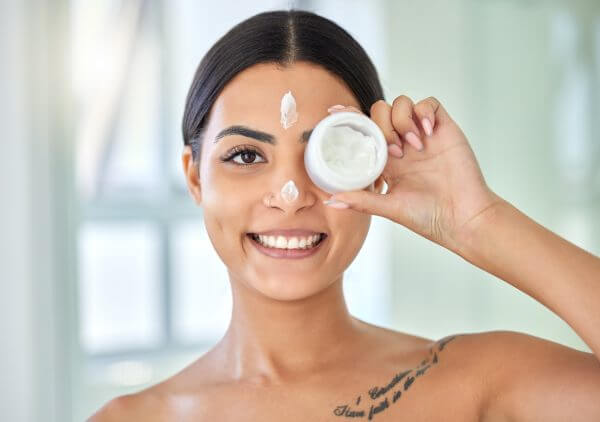 shot of a young woman applying cream to her face in a bathroom at home.