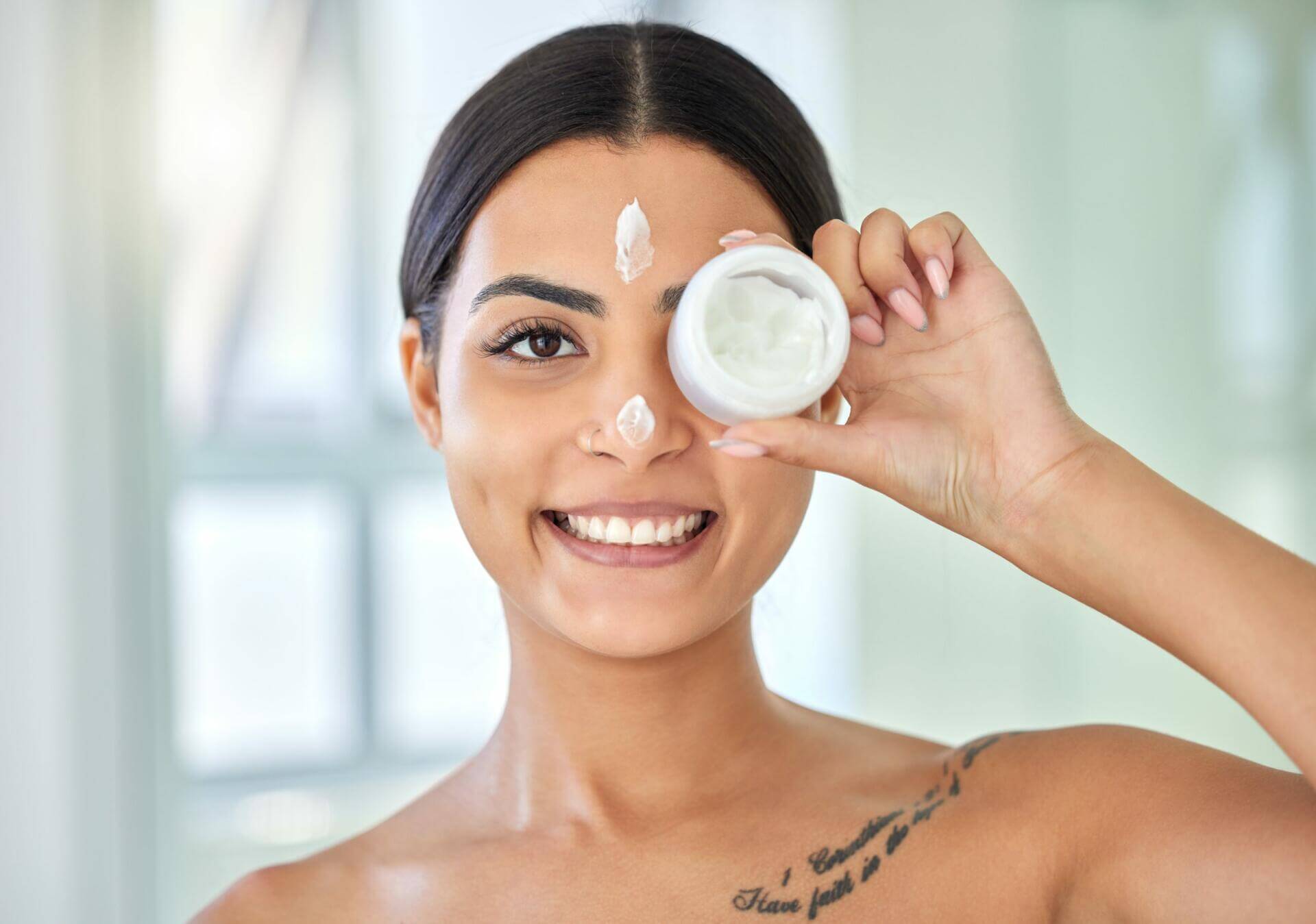 shot of a young woman applying cream to her face in a bathroom at home.