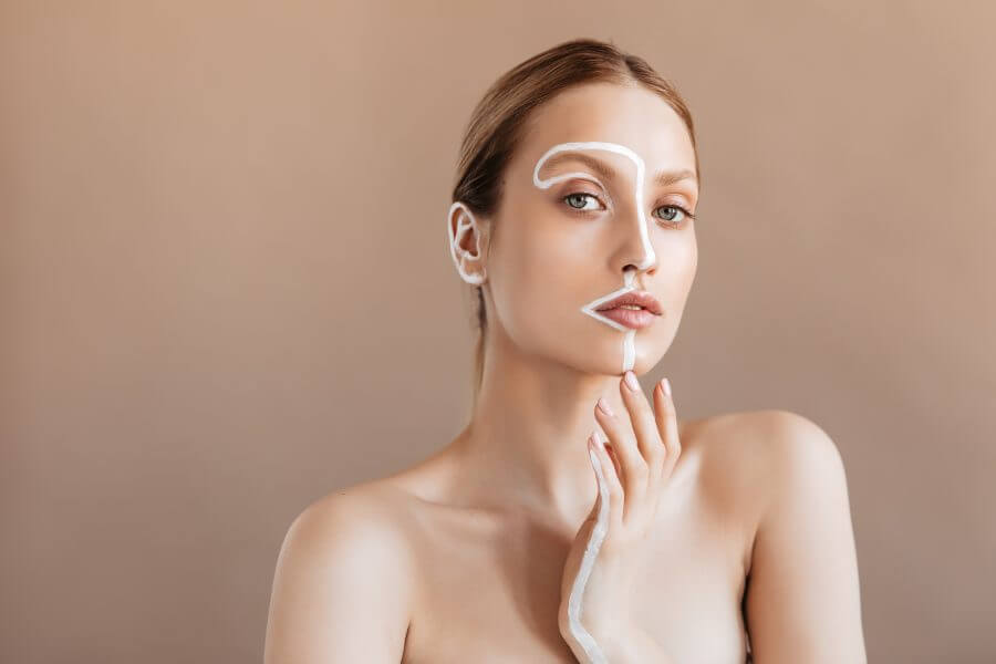 young woman without makeup with clean skin looks into camera on beige background. portrait of girl