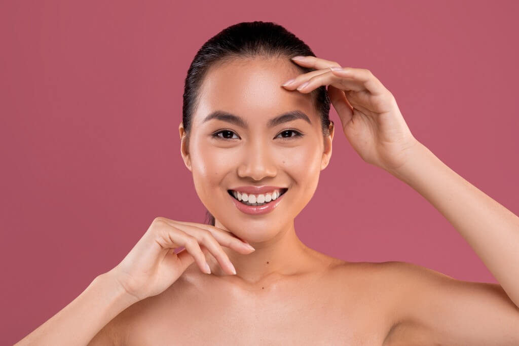 cheerful attractive asian lady posing topless on studio background