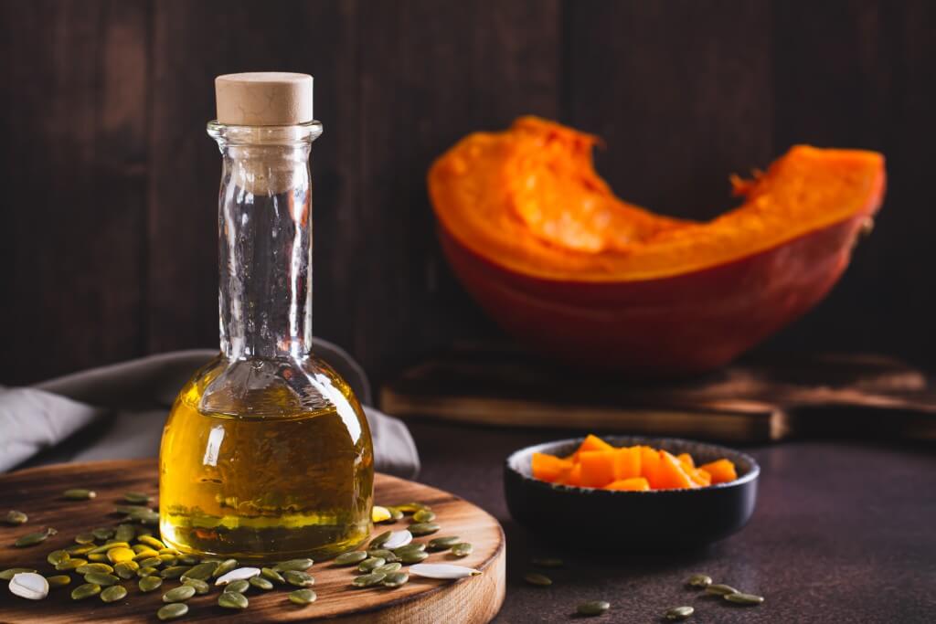 fresh pumpkin seed oil and pumpkin pieces on the table