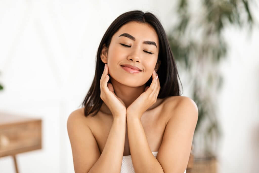 joyful asian lady touching her smooth face