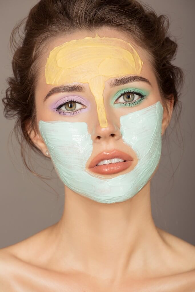 portrait of beautiful woman with colorful cream mask on her face