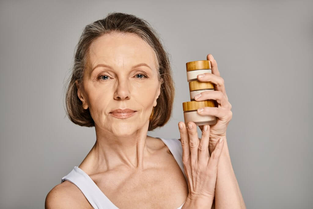 mature woman holding two jars of skin care products.