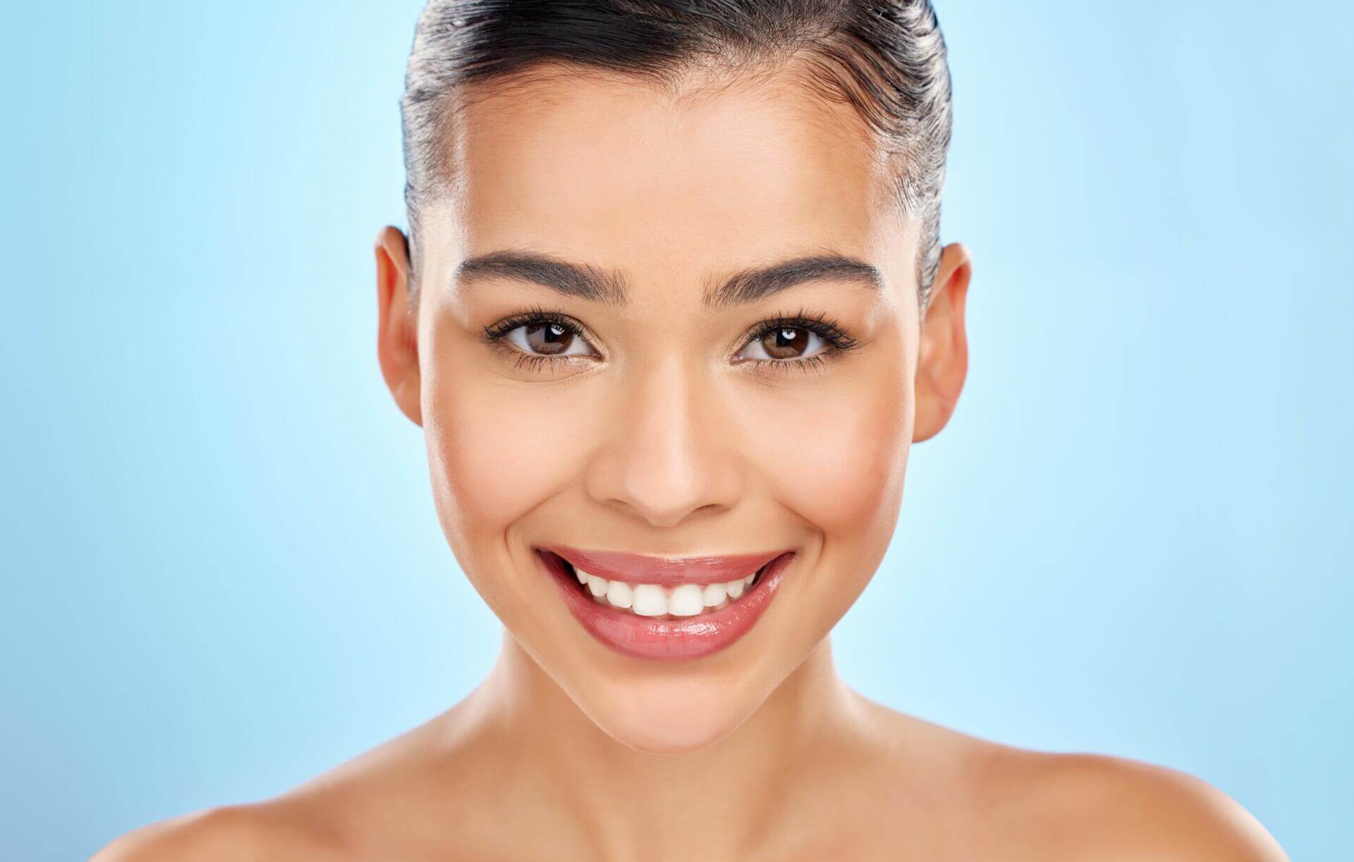 studio portrait of an attractive young woman posing against a blue background.