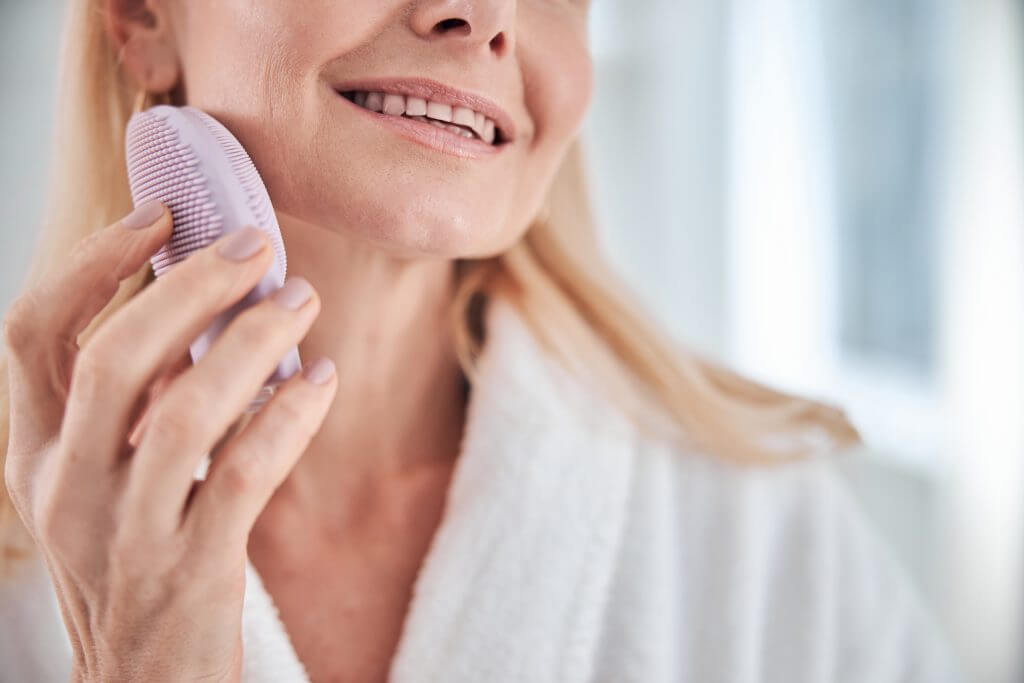 woman holding skin care device for cleaning in bathroom