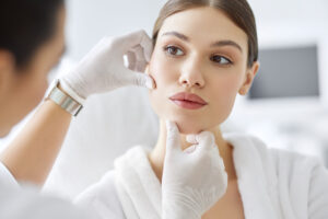 cosmetologist in gloves checking face of woman