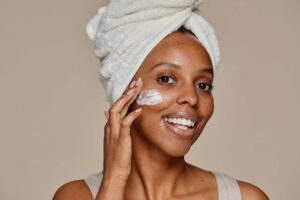 smiling black woman applying face cream 2023 11 27 05 20 59 utc